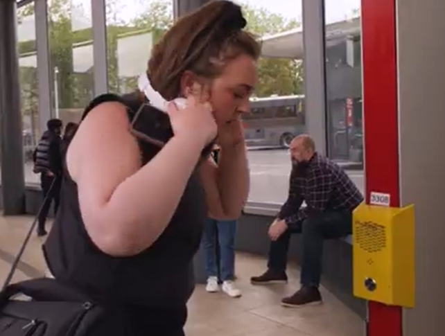 Image shows a female passenger using a help point to talk to the CCTV operator.